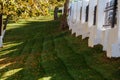 Autumn Background. Autumn garden with fallen leaves on the green grass, and a white fence on a Sunny day Royalty Free Stock Photo