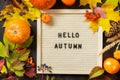 Autumn background with Hello Autumn letters and autumn message board, pumpkins and colorful leaves. Cozy autumn mood. Fall seasons Royalty Free Stock Photo