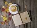 Autumn background on a wooden table with autumn dry colored leaves, white cup of coffee and a notepad with a pencil Royalty Free Stock Photo
