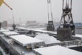 Autumn bad weather, snow, loading coal into the holds of industrial ships in the seaport Royalty Free Stock Photo