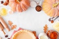 Autumn baking frame with pumpkin pie ingredients over a white marble background