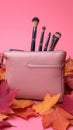 Autumn beauty essentials Pink leather clutch, makeup brushes, and leaves