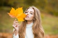 Autumn beauty. Woman fashion wodel with fall maple leaf outdoors. Young woman enjoying warm weather. People on yellow