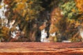 Autumn bokeh background with wooden plank in focus. Blurred fall nature with brown table