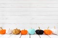 Autumn border of colorful pumpkins in a row with a white wood background