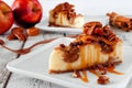 Autumn caramel apple pecan cheesecake slices, side view table scene against white wood