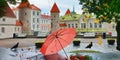 Autumn in the city park bench pink umbrella yellow leaves birds medieval towels red roof  and rainy drops green yellow tree leaves Royalty Free Stock Photo