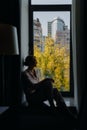 Autumn cityscape through the window. Out of focus girl looking out the window Royalty Free Stock Photo