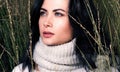 Autumn closeup portrait in the tall grass. Beautiful young woman in sweater and scarf