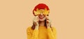 Autumn color style outfit, portrait of beautiful smiling young woman covering her eyes with yellow maple leaves wearing red french Royalty Free Stock Photo