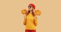 Autumn color style outfit, portrait of beautiful smiling young woman with yellow maple leaves wearing red french beret hat, Royalty Free Stock Photo