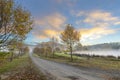 Autumn colored trees and clouds colored yellow by the rising sun Royalty Free Stock Photo