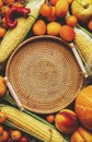 Autumn colorful vegetables and fruits set: apricots, tomatoes, pumpkin, paprika, corn, etc. and empty wicker tray on rustic wooden Royalty Free Stock Photo