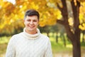 Autumn is coming! Be happy today! Close up portrait of young handsome brunette man staying in autumn park smiling