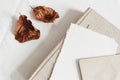 Autumn composition. Blank greeting card mockup, craft envelope and dry beech leaves on white linen table cloth