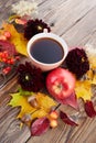 Autumn composition - coffee, maple leaves and flowers on wooden background. Seasonal autumn concept with drink.