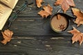 Autumn composition. Cup of coffee, open book, eyeglasses, maple leaves on black wooden background with copy space, top Royalty Free Stock Photo