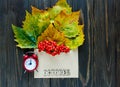 Autumn composition with envelope and leaves, berries in it next to word October by letters, red clock and cup of coffee