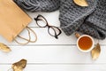 Autumn composition. Feminine desk table with knitted scarf, tea cup, glasses, shopping bag, fall leaves on wooden white background Royalty Free Stock Photo