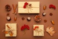 Autumn composition and gifts on brown background. Pattern made of autumn leaves, acorn, pine cones