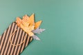 Autumn composition with golden leaves in gift bag on green paper background. Fall mockup with gold maple leaves. Flat lay, top Royalty Free Stock Photo