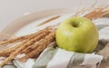 An autumn composition of a green apple on a cotton napkin next to a bouquet of dried flowers. Warm colors