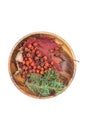 Autumn composition of natural ingredients. Overripe rowan berries, sprig of prickly green juniper and maple leaf in wooden bowl Royalty Free Stock Photo