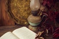 Autumn composition with an old kerosene lamp, an old tray and an open book and red grape leaves on a wooden table