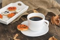 Autumn composition of orange and white cookies for Halloween, cups of fragrant black coffee stands on brown wooden table