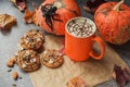 Autumn composition of pumpkins, mug of coffee, almond, spider and Halloween Cookies with ghosts, spiderweb on dark stone table.