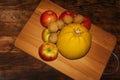 Autumn composition. Ripe red apples, walnuts, pumpkin on a wooden chopping Board. Dark rustic background