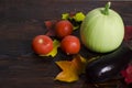 Autumn composition, ripe tomatoes, zucchini, eggplant, fallen leaves on a dark wooden background. harvest, thanksgiving.