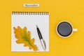 Autumn composition. Text November Coffee Cup, open notepad with pen and yellow oak leaf on yellow paper background. Top view Flat