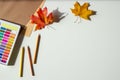 Autumn composition. Watercolor paint, colored pencils and autumn maple fall leaves on white desk background. Top view Royalty Free Stock Photo