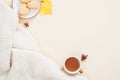 Autumn composition. White knitted plaid, cup of tea, cookies, fallen leaves on pastel beige background. Flat lay, top view, copy