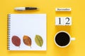 Calendar November 12 cup of coffee, notepad with pen and yellow leaf on yellow background Royalty Free Stock Photo