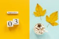 Autumn composition. Wooden calendar September 3, cup of cocoa with marshmallows and yellow autumn leaves on yellow blue Royalty Free Stock Photo