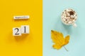 Autumn composition. Wooden calendar September 21, cup of cocoa with marshmallows and yellow autumn leaves on yellow blue Royalty Free Stock Photo