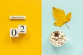 Autumn composition. Wooden calendar September 2, cup of cocoa with marshmallows and yellow autumn leaves on yellow blue Royalty Free Stock Photo