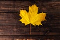 Autumn composition. Yellow maple leaf in the center of dark wooden brown background. Thanksgiving day concept. Flat lay, top view Royalty Free Stock Photo