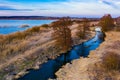 Autumn concept. Dried grass and trees surrounded by blue lake and narrow river, aerial landscape Royalty Free Stock Photo