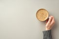Autumn concept. First person top view photo of young woman`s hand in sweater holding cup of frothy coffee on isolated grey Royalty Free Stock Photo