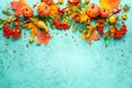 Autumn concept with pumpkins, flowers, autumn leaves and rowan berries on a turquoise background. Festive autumn decor, flat lay