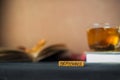 Autumn concept. Tea in a transparent mug, unfolded book, yellow and red autumn leaves and spruce branches, cones and chestnuts on