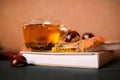 Autumn concept. Tea in a transparent mug, unfolded book, yellow and red autumn leaves and spruce branches, cones and chestnuts on