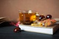 Autumn concept. Tea in a transparent mug, unfolded book, yellow and red autumn leaves and spruce branches, cones and chestnuts on