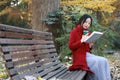 Young asian sensual woman reading a book sit bench in romantic autumn scenery.Portrait of pretty young girl in autumnal forest Royalty Free Stock Photo