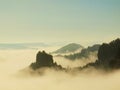 Autumn country. Deep misty valley full of morning heavy wisps of blue orange fog. Sandstone peaks increased from mist, dark hills Royalty Free Stock Photo