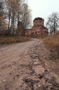 autumn country road in an abandoned village leading to an old dilapidated church, dry plants and birch trees with yellow leaves. Royalty Free Stock Photo