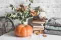 Autumn cozy home still life. Pumpkin, dry branch pitcher, stack of books, pile of winter autumn sweaters,  teddy bear on the Royalty Free Stock Photo